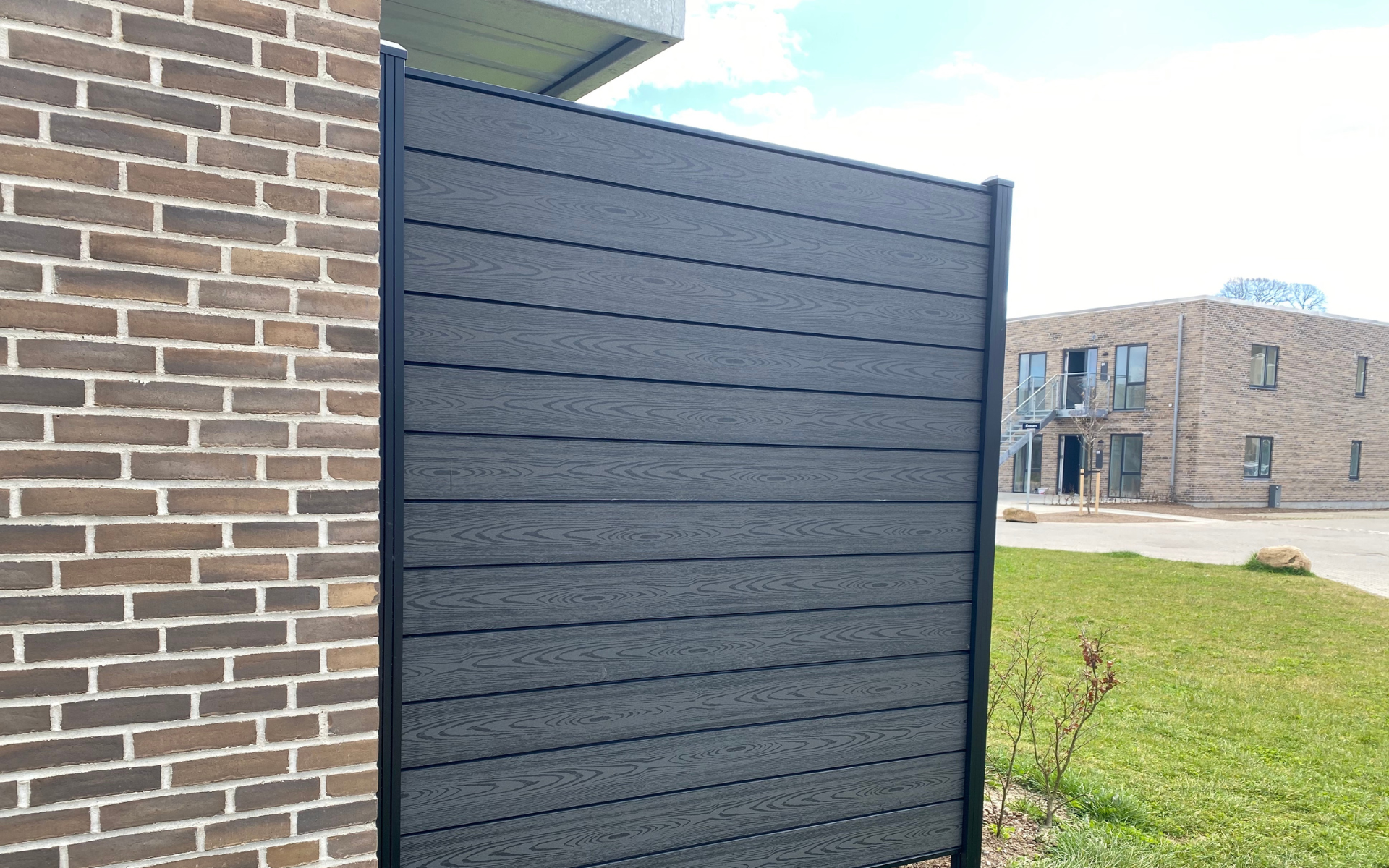 Flot komposithegn der sidder fastgjort på en mur.